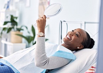 Woman smiling at reflection in handheld mirror