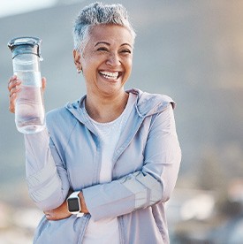 Woman smiling with water bottle on hike outside