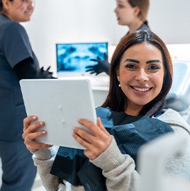 Woman smiling while holding mirror in treatment chair