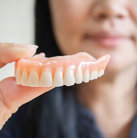 Dental team member holding a full upper denture