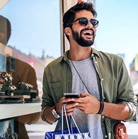 Man with sunglasses smiling while shopping outside