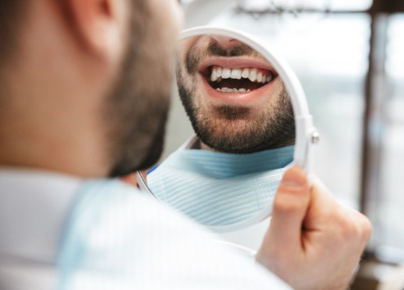 Patient smiling at reflection in handheld mirror
