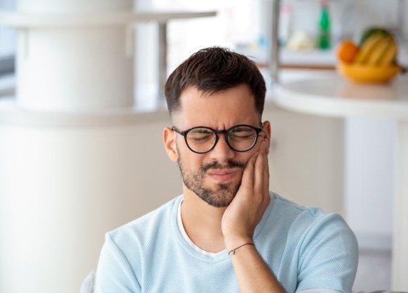 Man with black glasses experiencing toothache