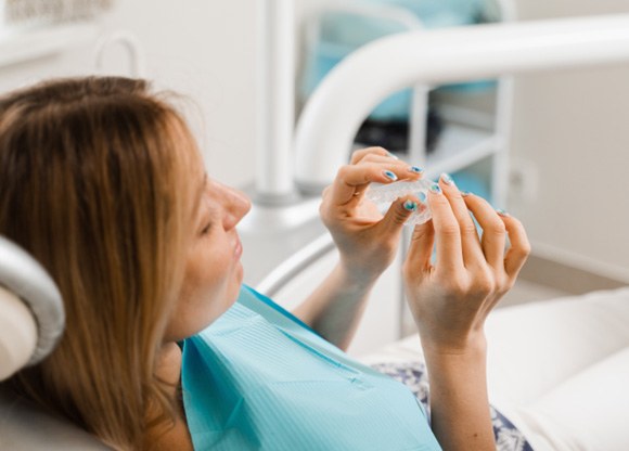Patient holding clear aligner in treatment chair